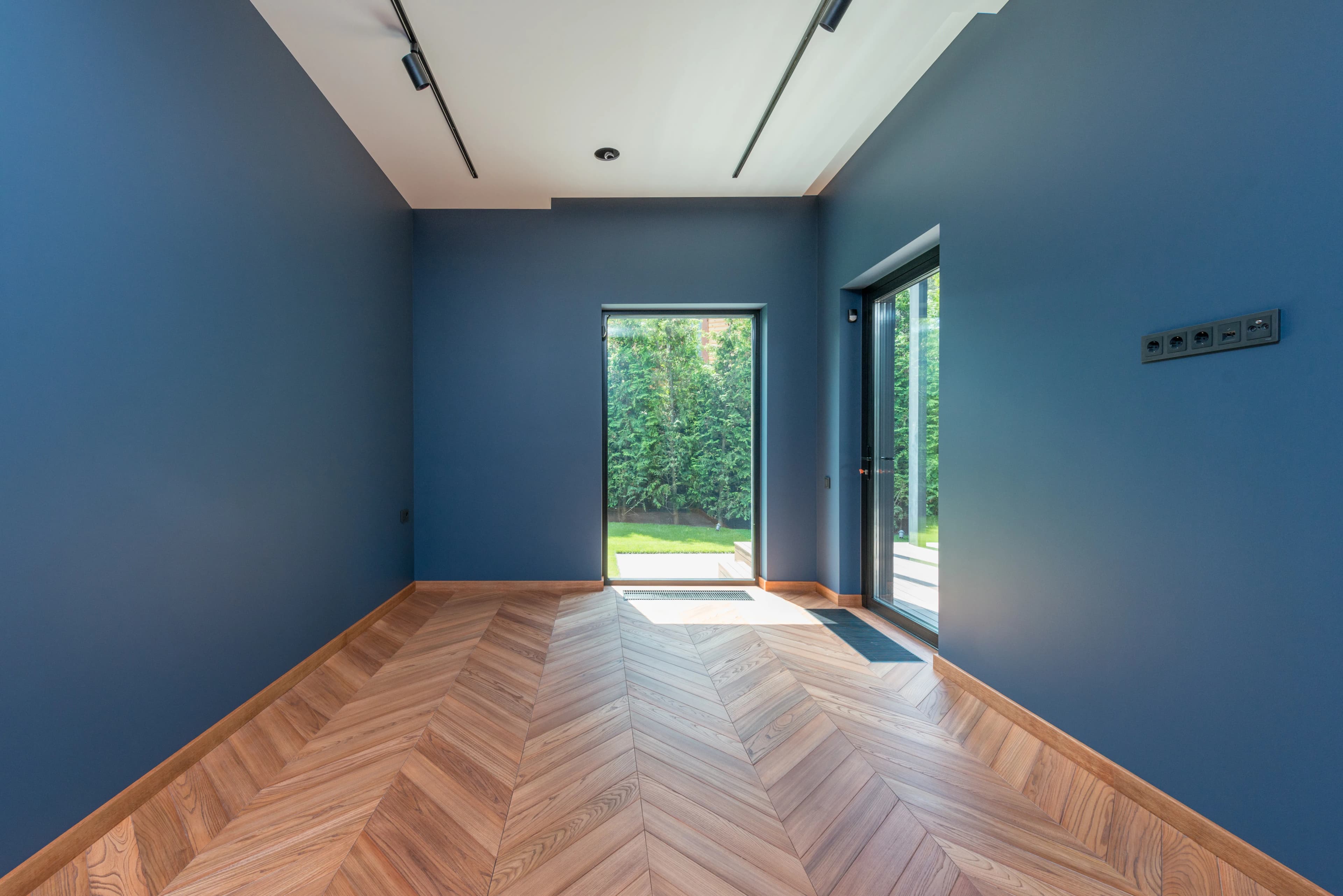 Room with a timber herringbone floor and glass doors to the garden