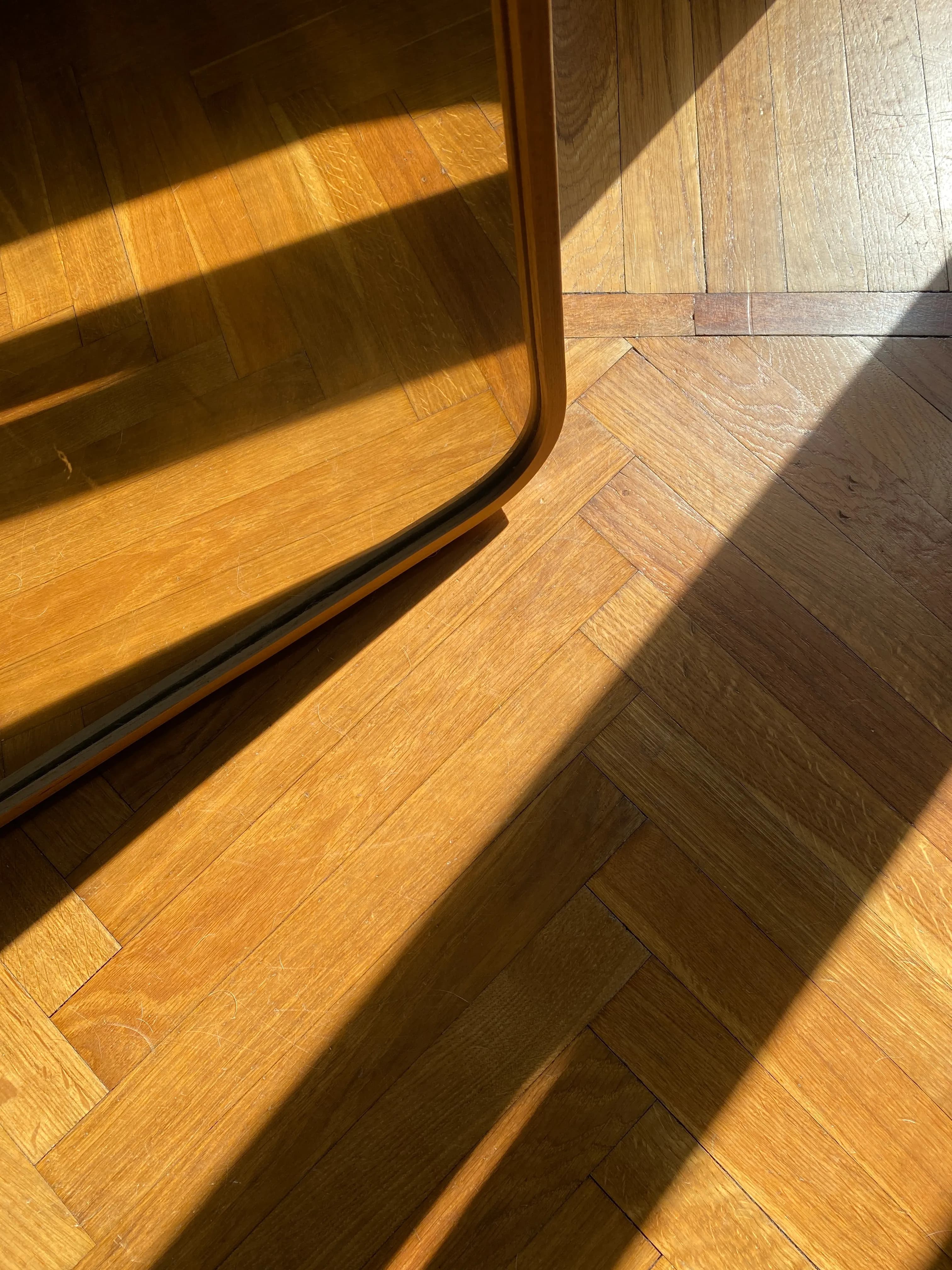 Sunlight falling across a herringbone timber floor